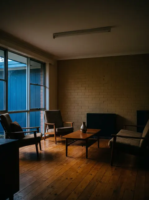 A 1960s living room at dusk with the old lights off