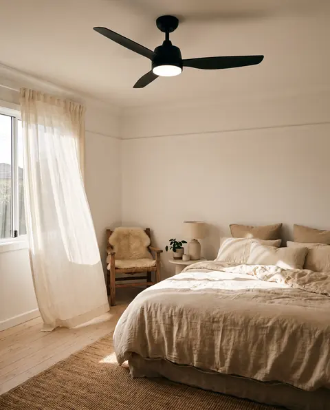 Matte black ceiling fan with a light in a bright coastal bedroom